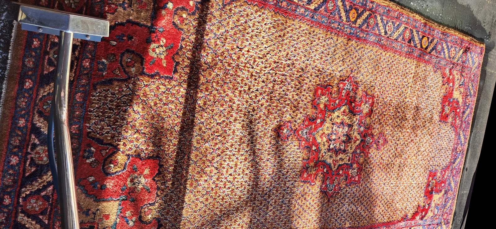 A Persian rug mid-wash on the True Clean wash floor, the extraction wand across one corner